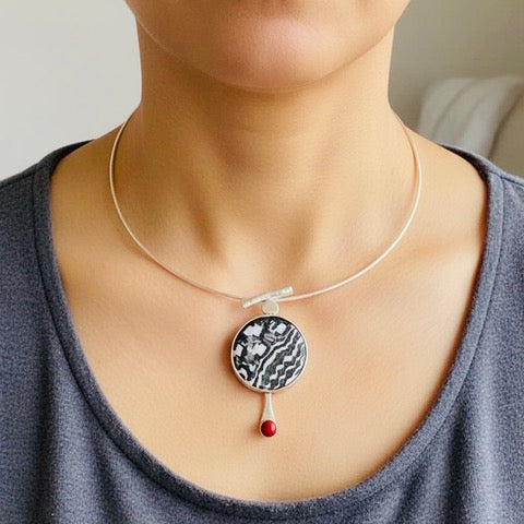 Black and white enamel pendant with red coral stone, handcrafted by Laura Haszard